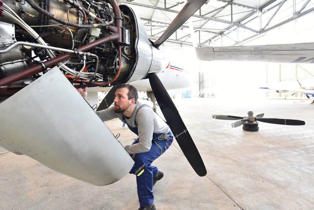 A man is working on the engine of an airplane in a hangar.