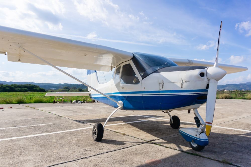 A small blue and white airplane is parked on a runway.