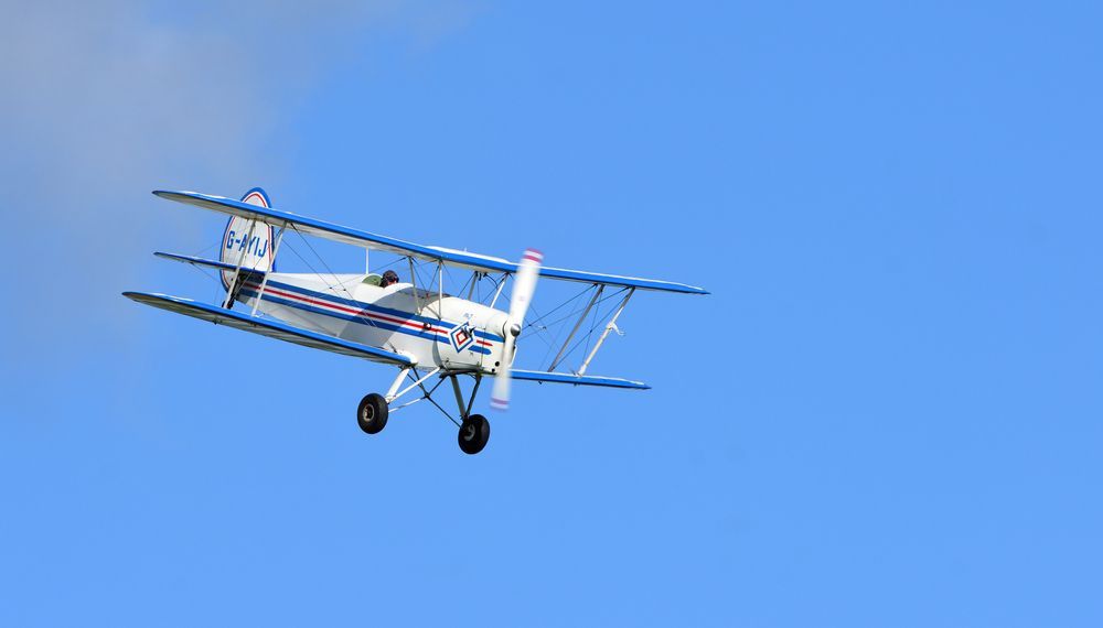 A small plane is flying through a clear blue sky.