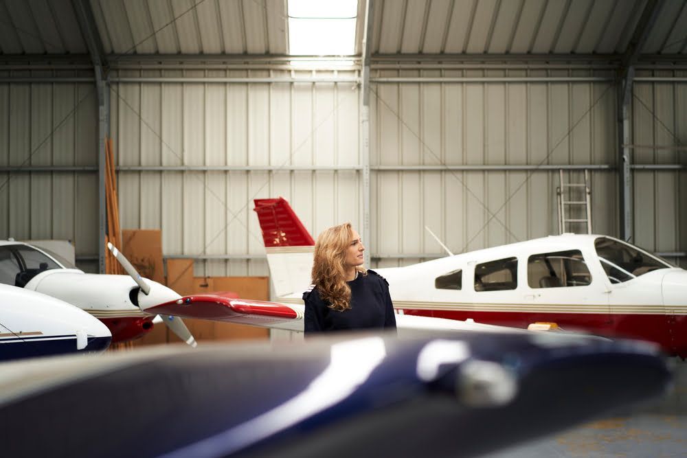 A woman is standing in a hangar next to a plane.