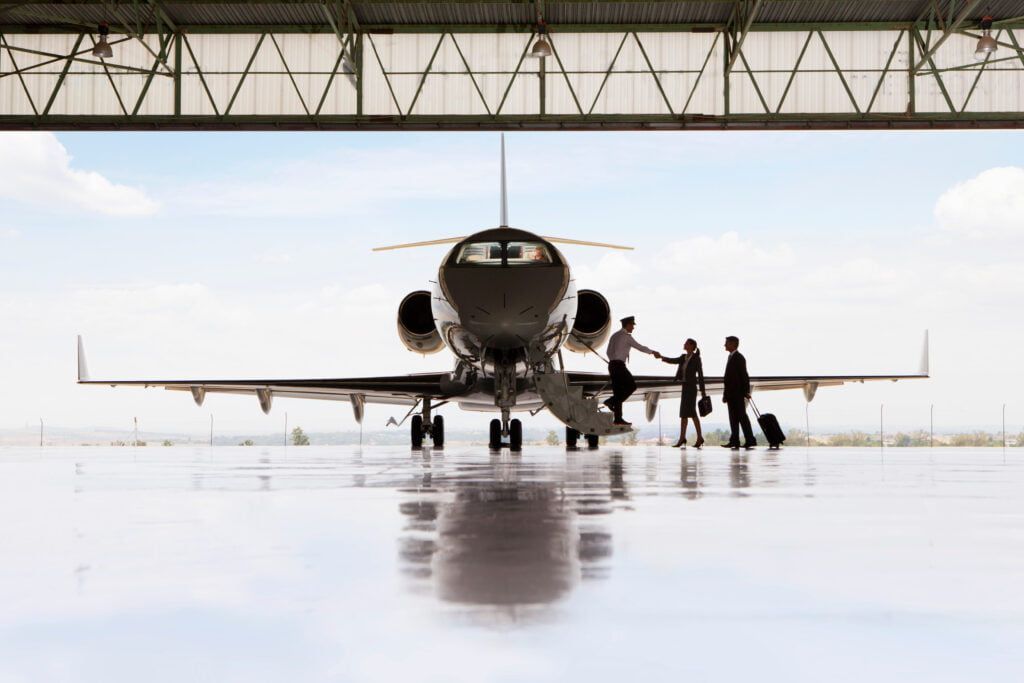 A group of people are boarding a private jet in a hangar.