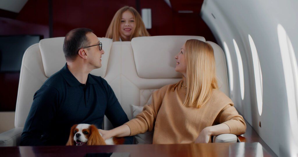 A man , woman and child are sitting on a private jet with a dog.