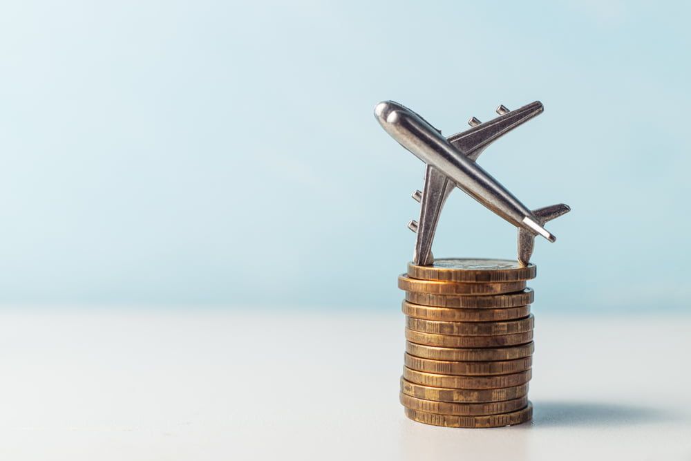 A toy airplane is sitting on top of a pile of coins.