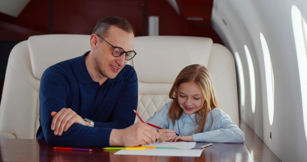 A man and a little girl are sitting at a table on an airplane.