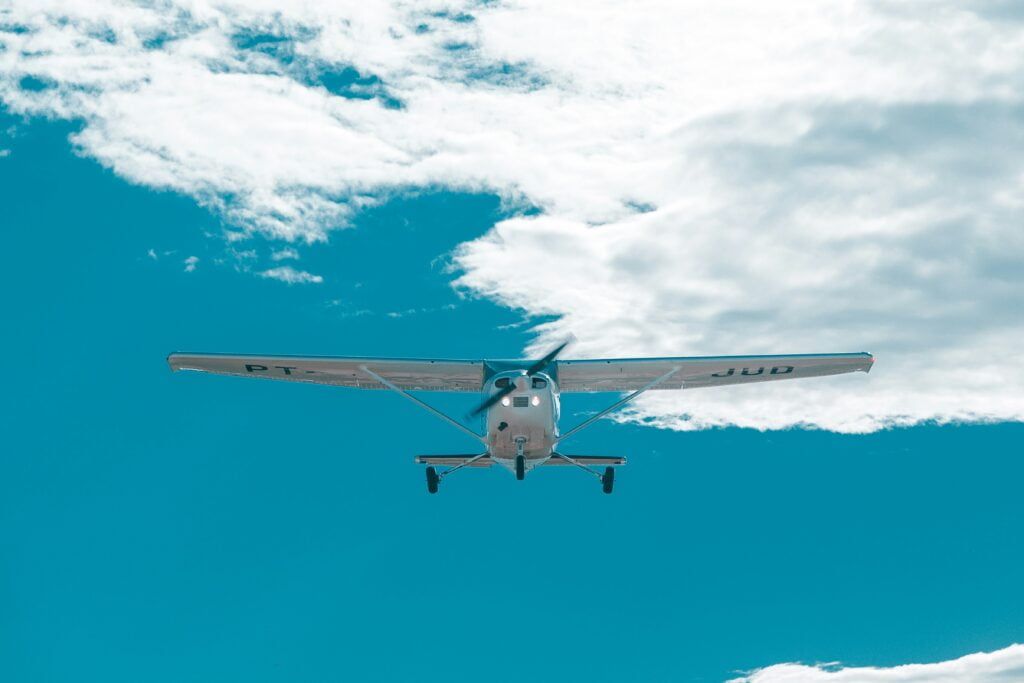 A small plane is flying through a cloudy blue sky.