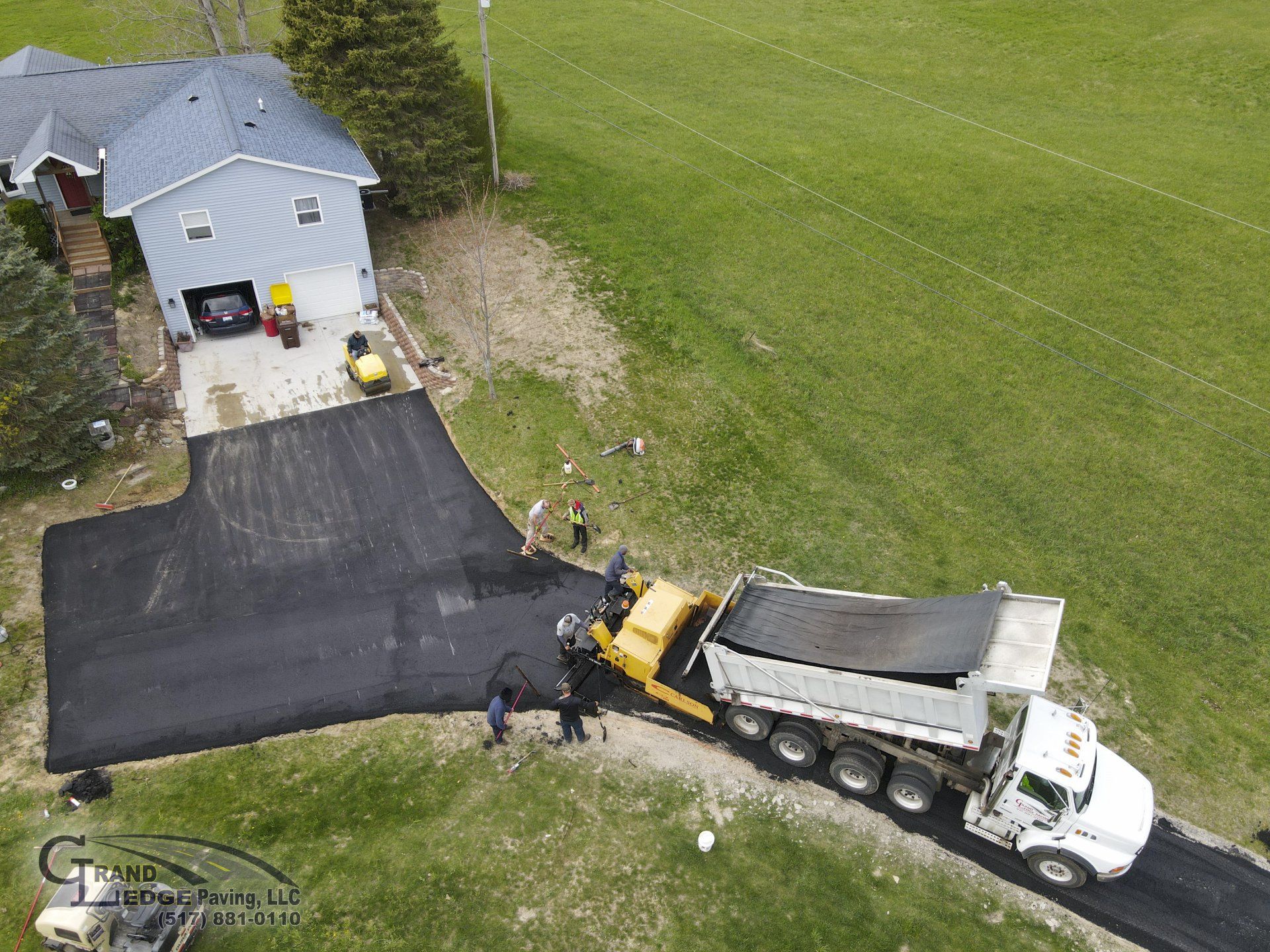 An aerial view of a dump truck driving down a road next to a house.