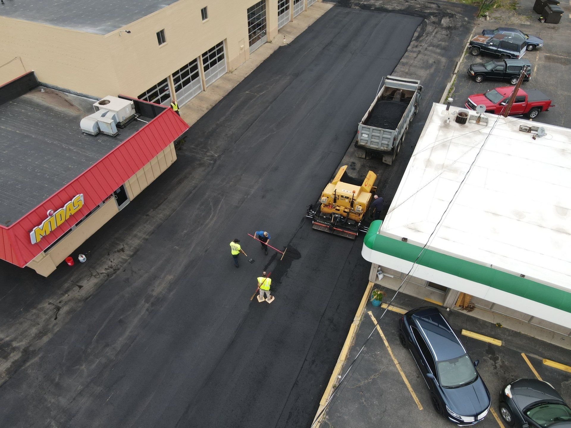 An aerial view of a road being paved next to a gas station