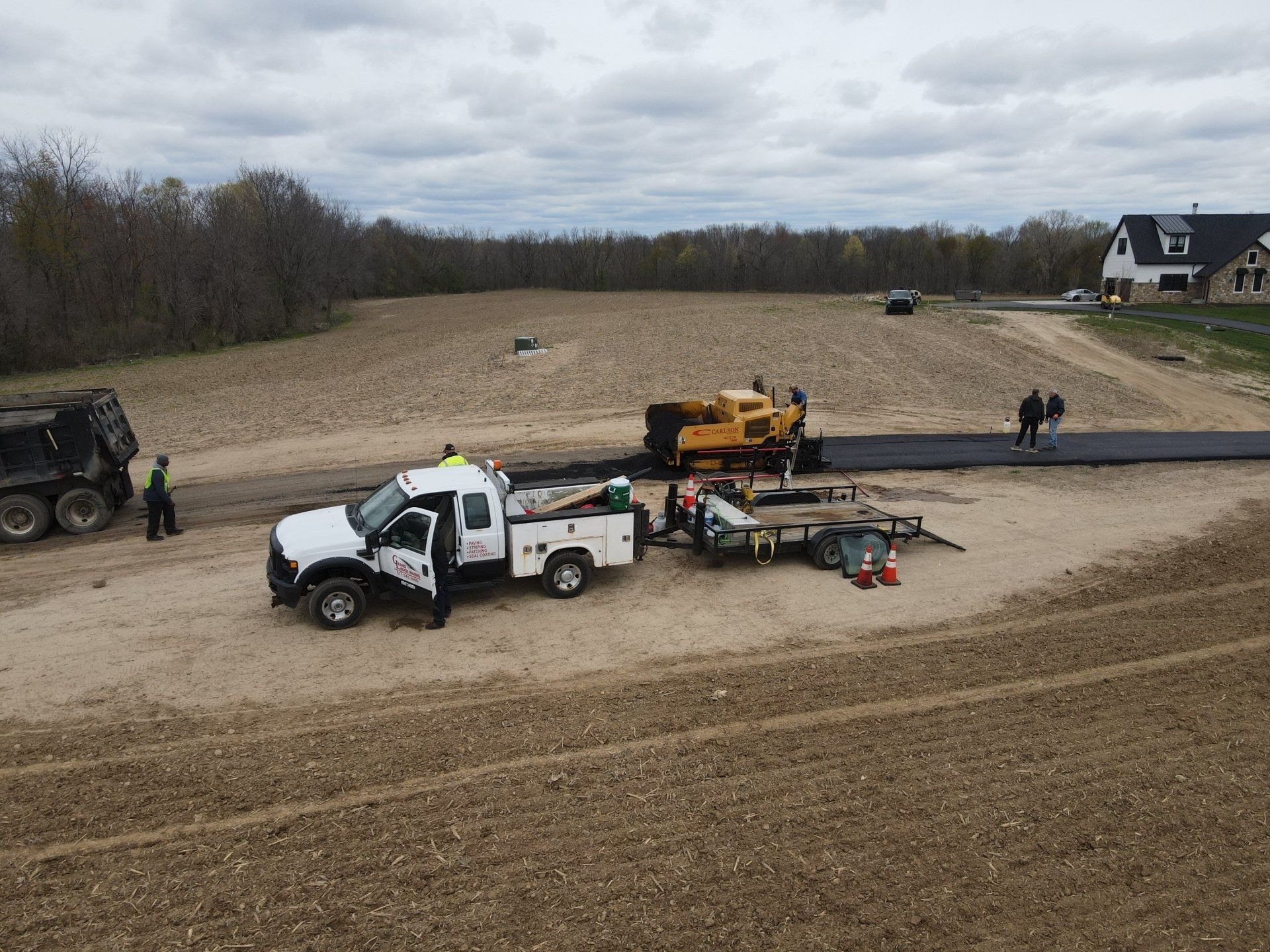 A white truck is parked in a dirt field next to a yellow truck.
