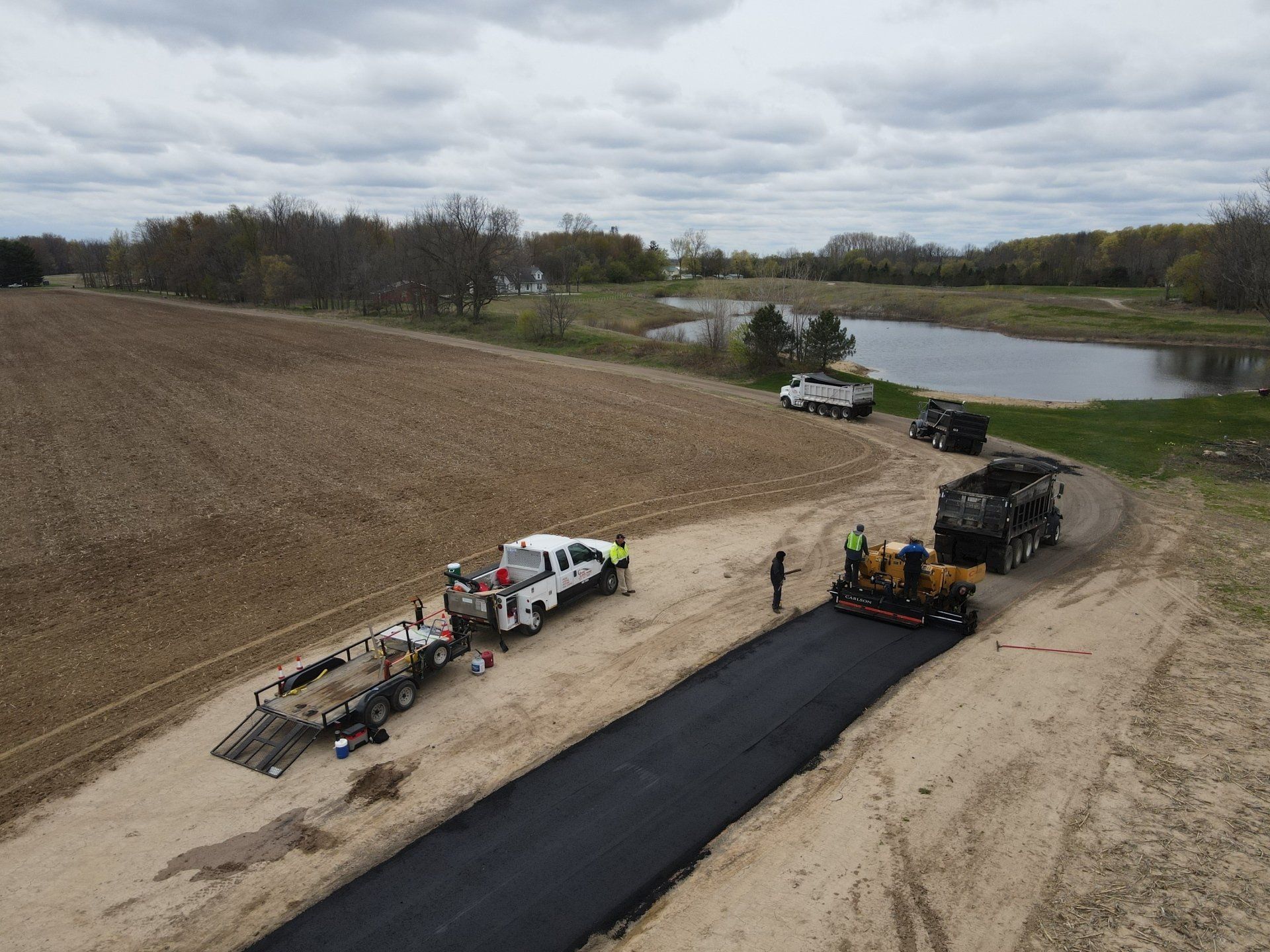 An aerial view of a road being paved in a field.