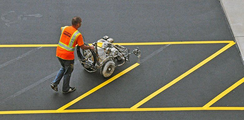 A man is painting yellow lines on a parking lot