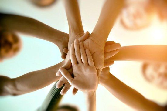 A group of people are putting their hands together in a circle.
