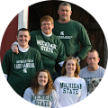 A group of people wearing michigan state shirts are posing for a picture.