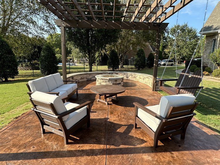 A patio with furniture and a fire pit under a pergola.