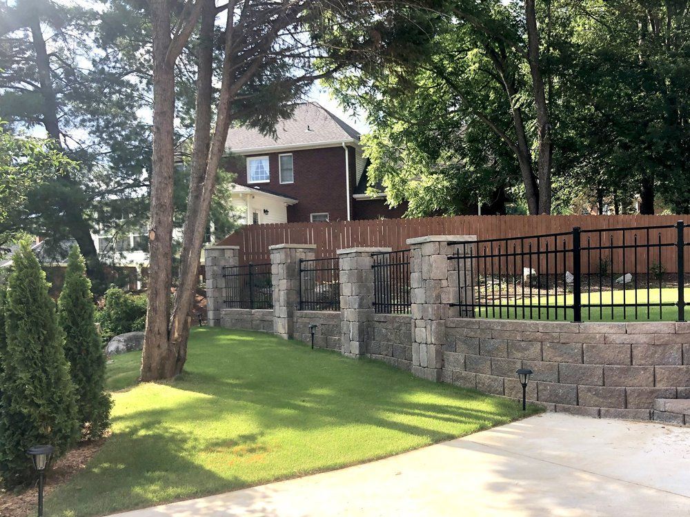 A house with a fence and a brick wall in front of it