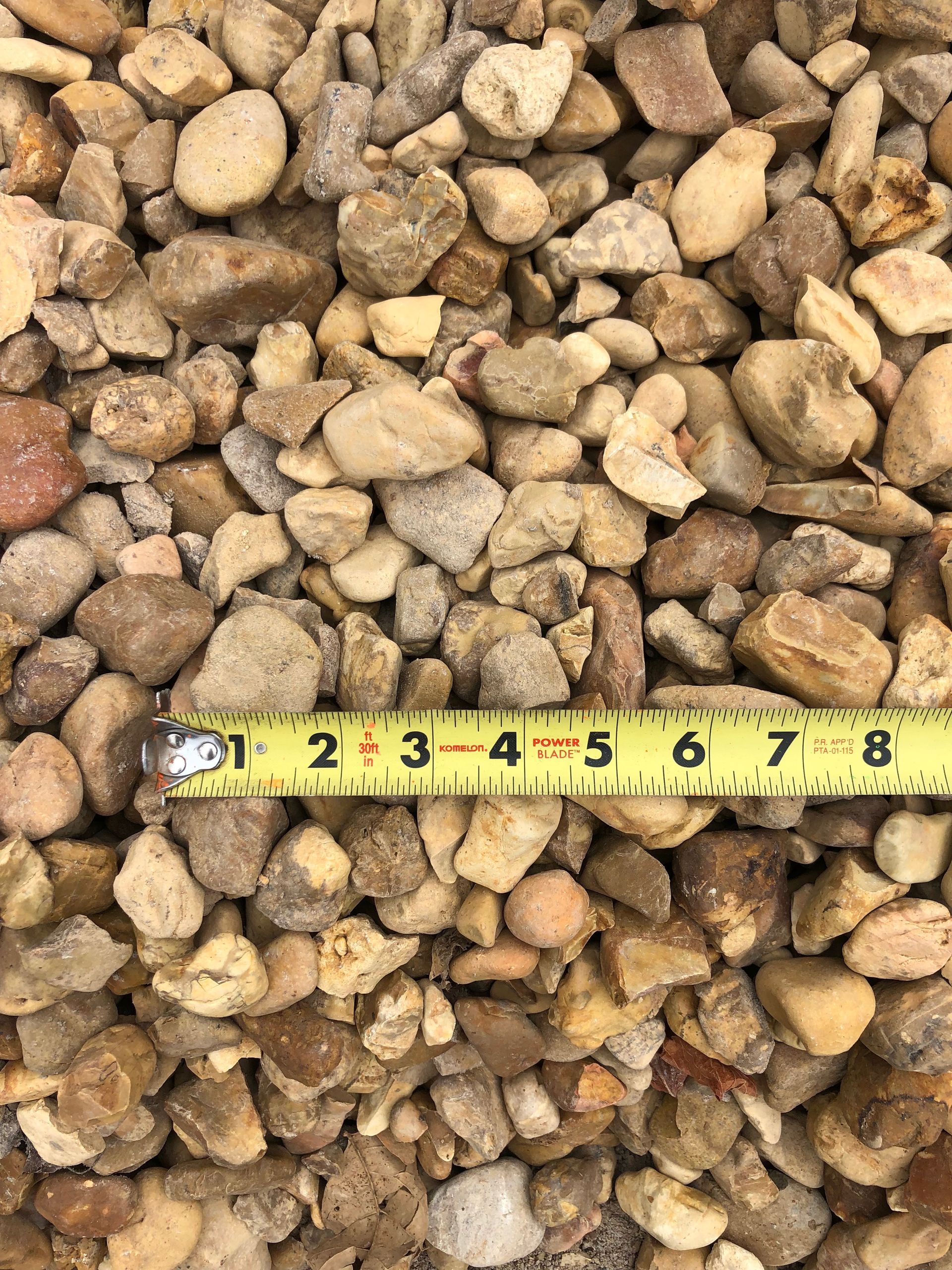 A yellow tape measure is sitting on top of a pile of rocks.