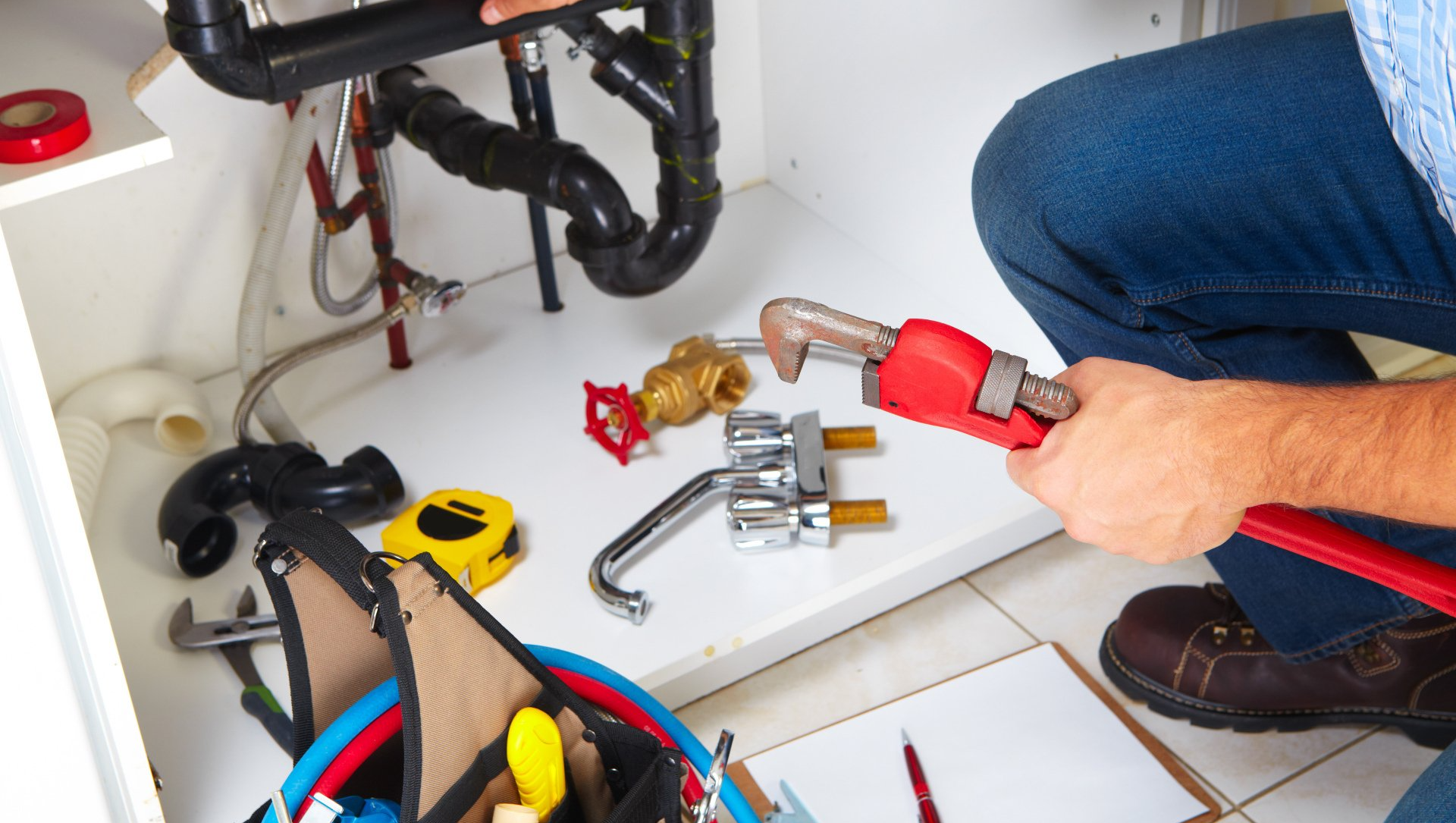 View under sink with plumber holding a wrench
