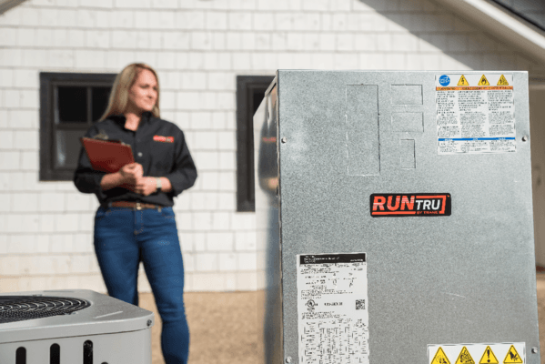 Woman standing with padfolio and HVAC equipment
