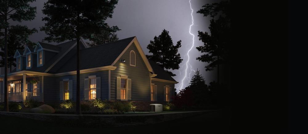Picture at night of house with lights on and lighting strike in the background