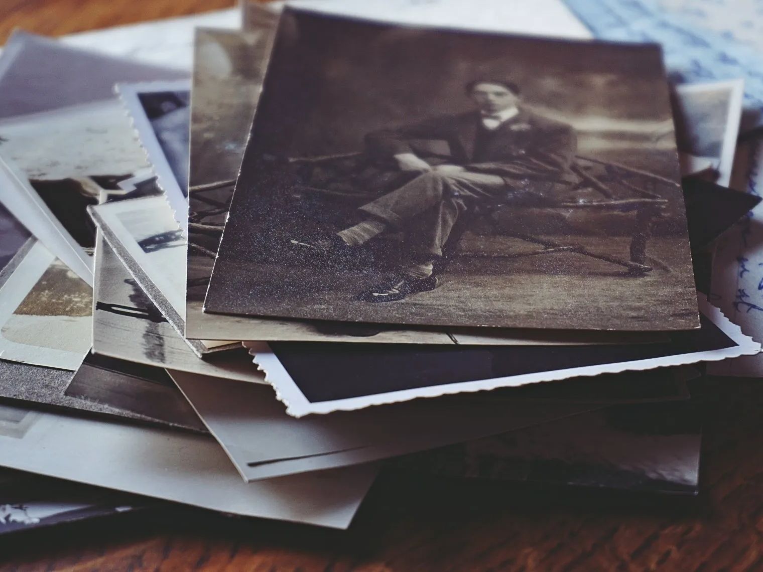 A stack of old photographs of a man sitting on a bench