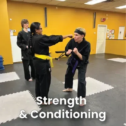 Martial arts class: Instructor demonstrating a punch, student in stance, others watching in a studio.