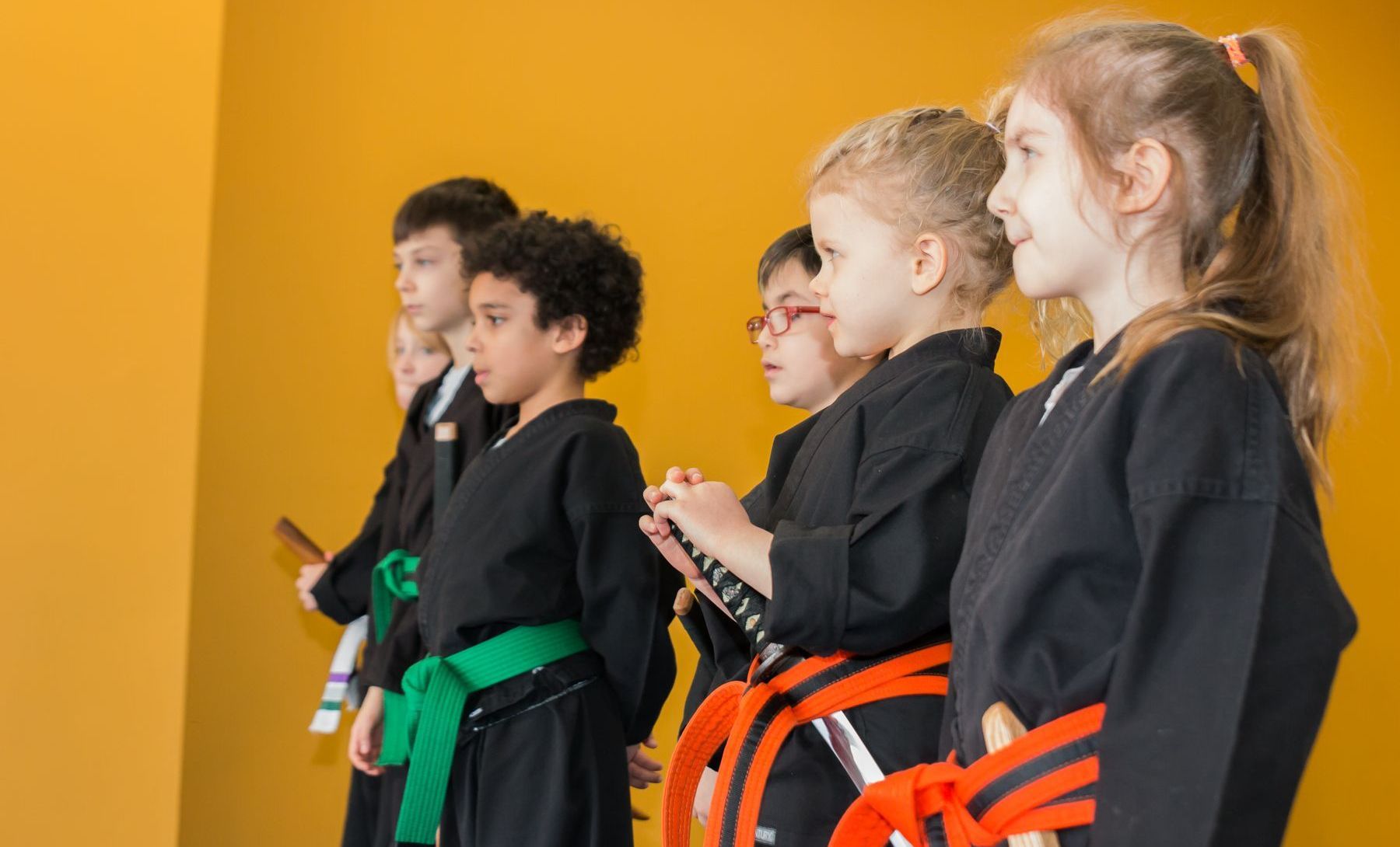 A group of young children are standing next to each other in a karate class.