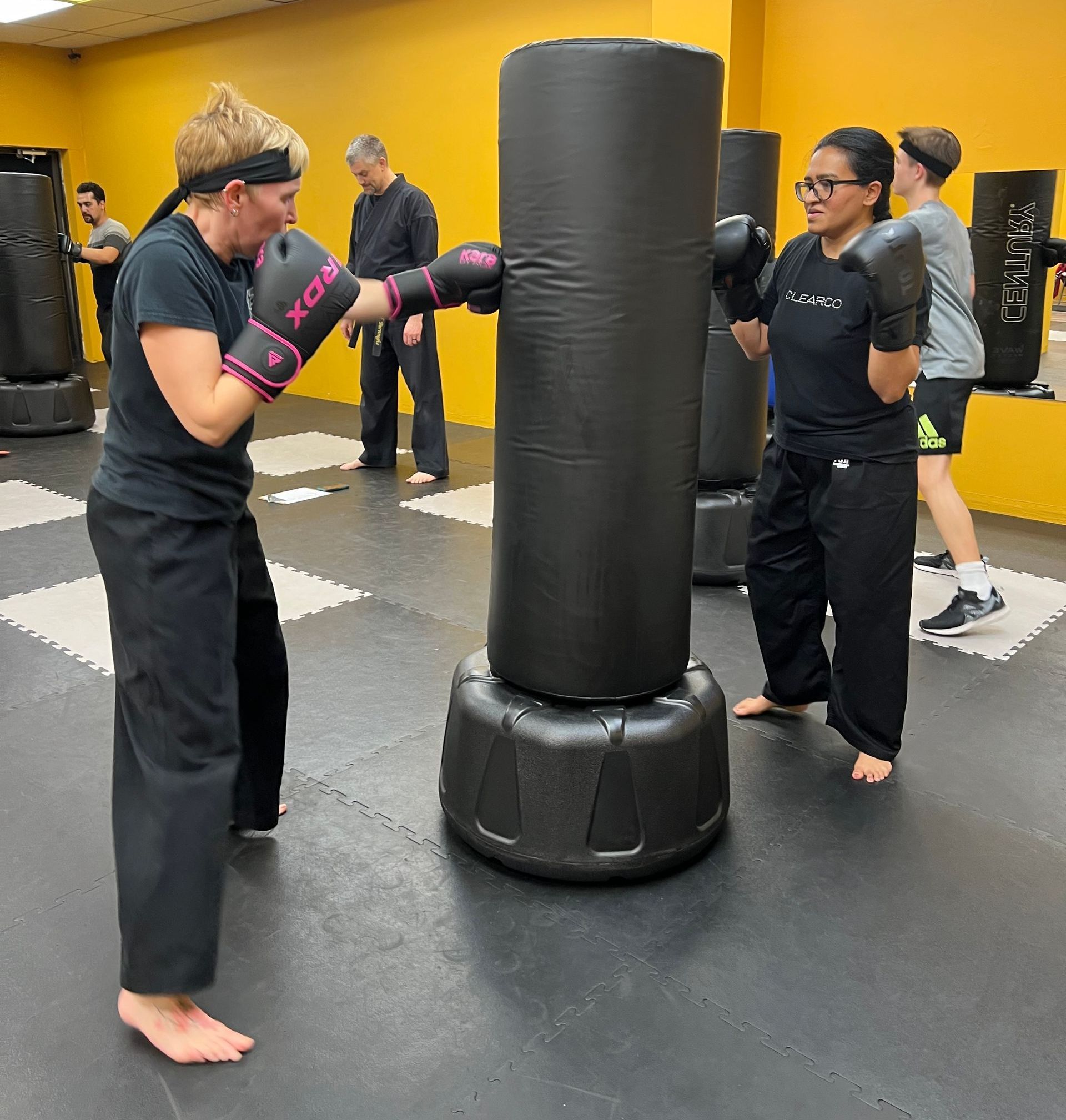 A group of people are practicing martial arts in a gym.  The image links to the Fitness Kickboxing Classes Page. 