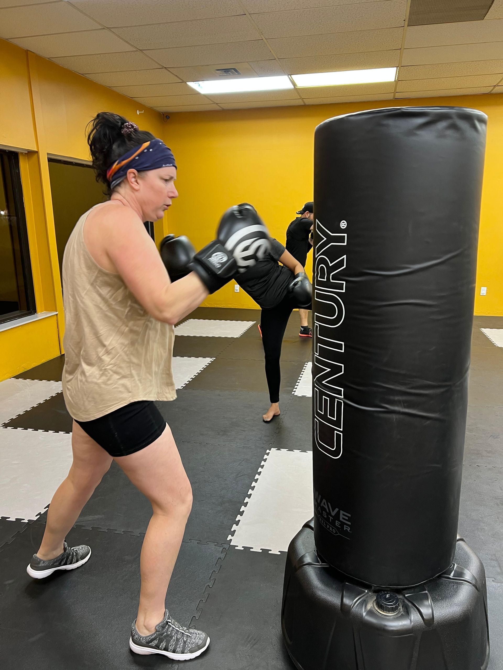 A group of people are practicing martial arts in a gym.  The image links to the Fitness Kickboxing Classes Page. 