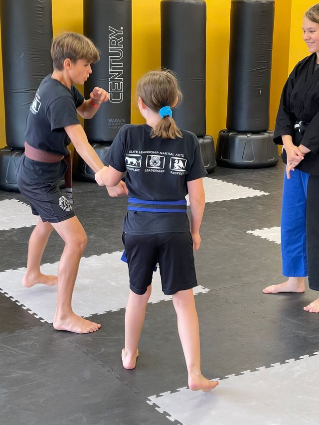 A boy and a girl are practicing martial arts in a gym.