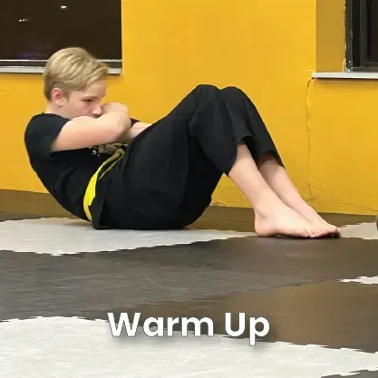 Child in karate uniform doing warm-up exercise on a padded floor with cones.