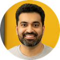 A man with a beard is smiling in front of a yellow wall.