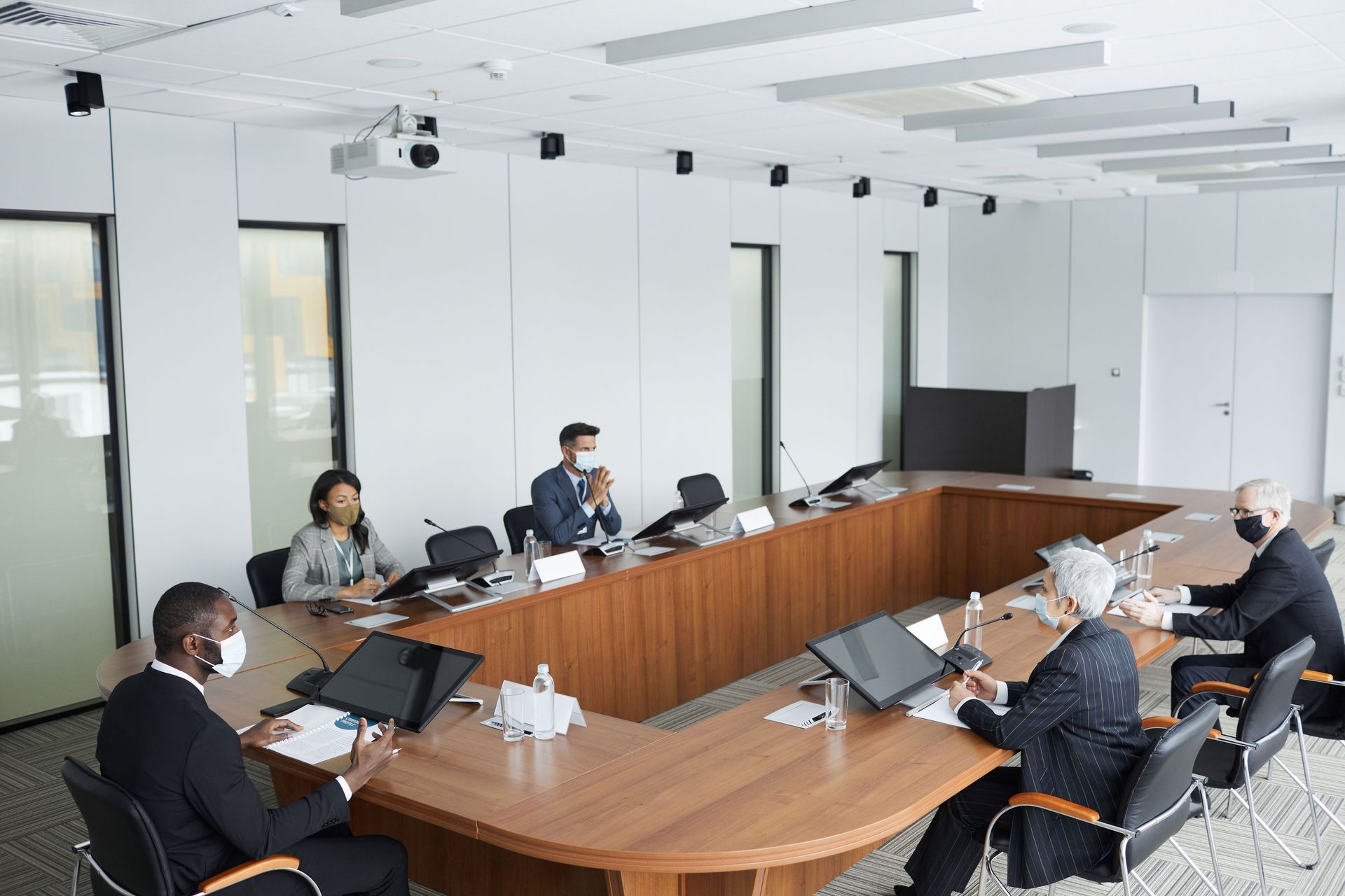 People seated around a conference table in a bright meeting room, using laptops and talking