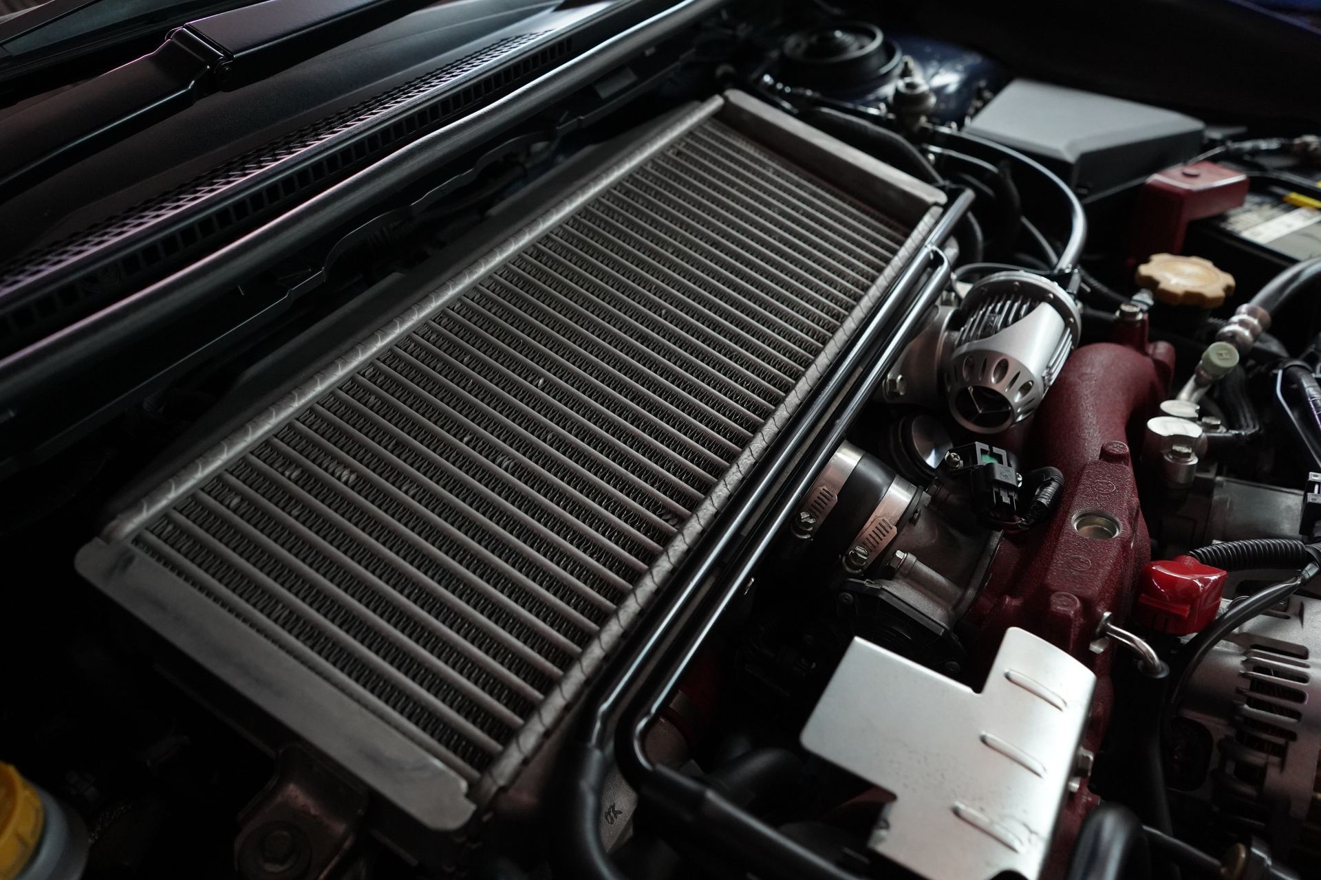 Car engine with exposed air filter, featuring metal grille, black and red components.