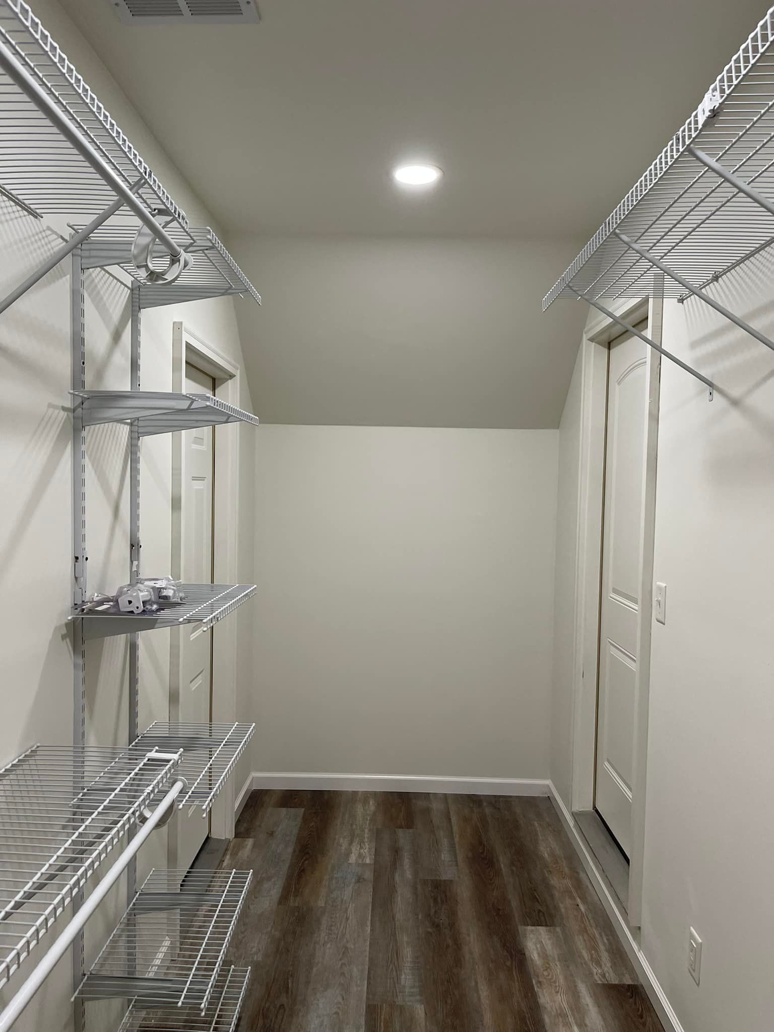 A walk in closet with lots of shelves and a wooden floor.