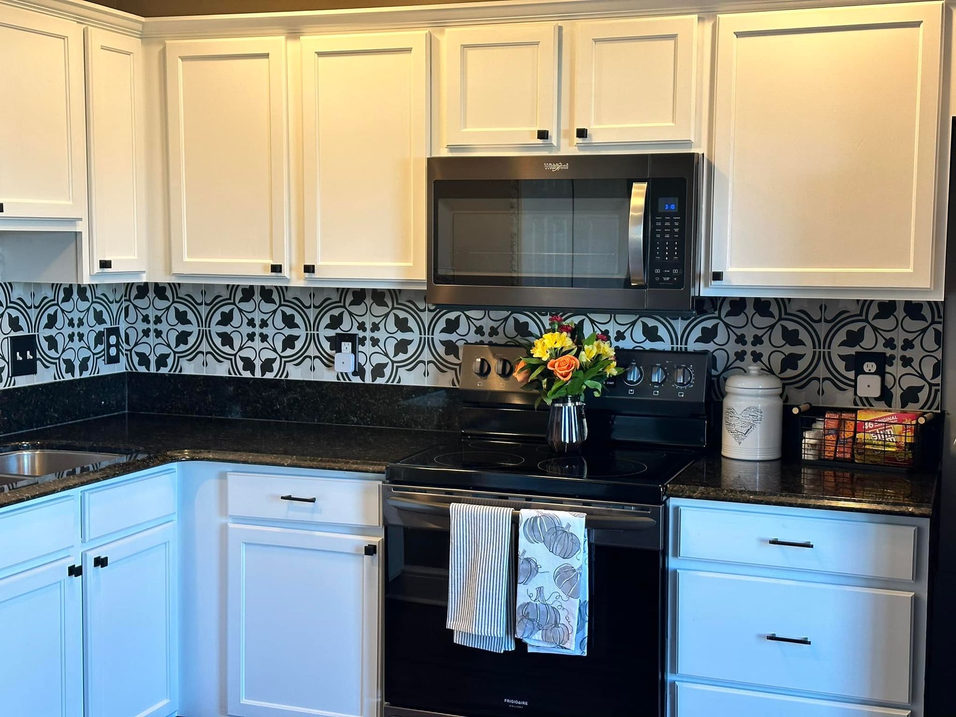 A kitchen with white cabinets and black counter tops
