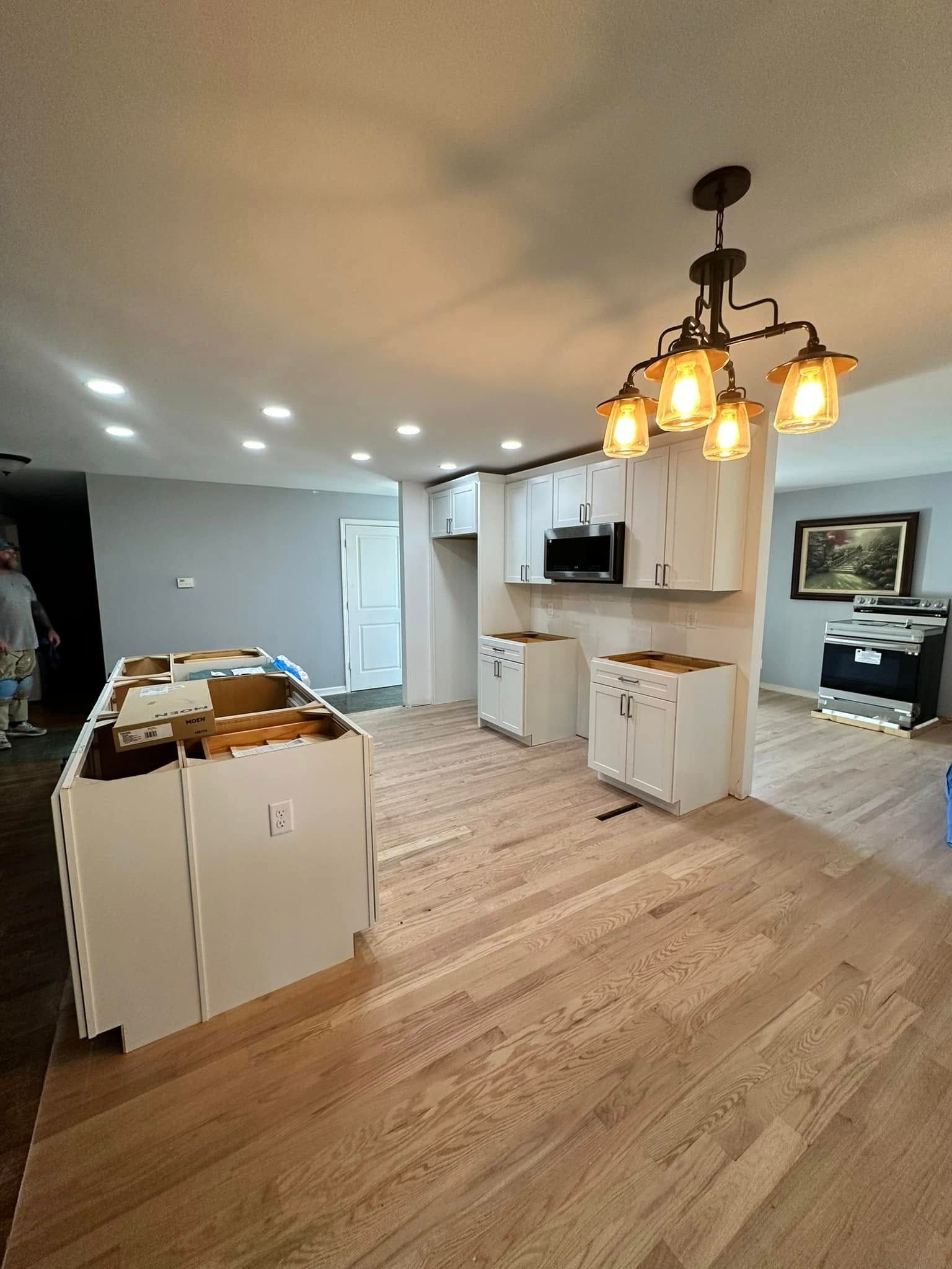 A kitchen with white cabinets and hardwood floors is being remodeled.