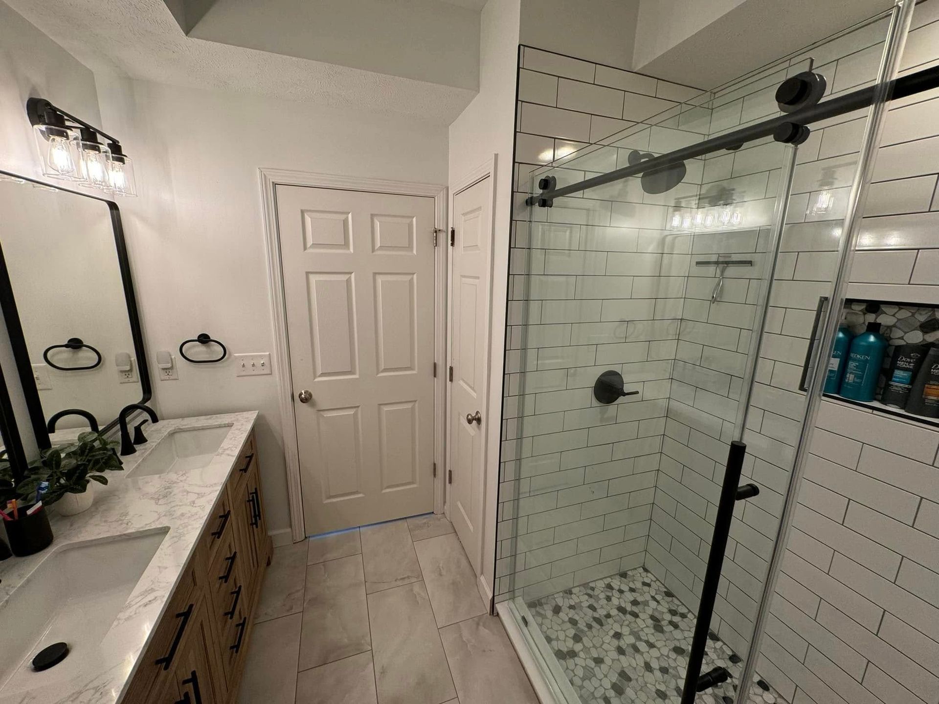 A bathroom with two sinks and a walk in shower.
