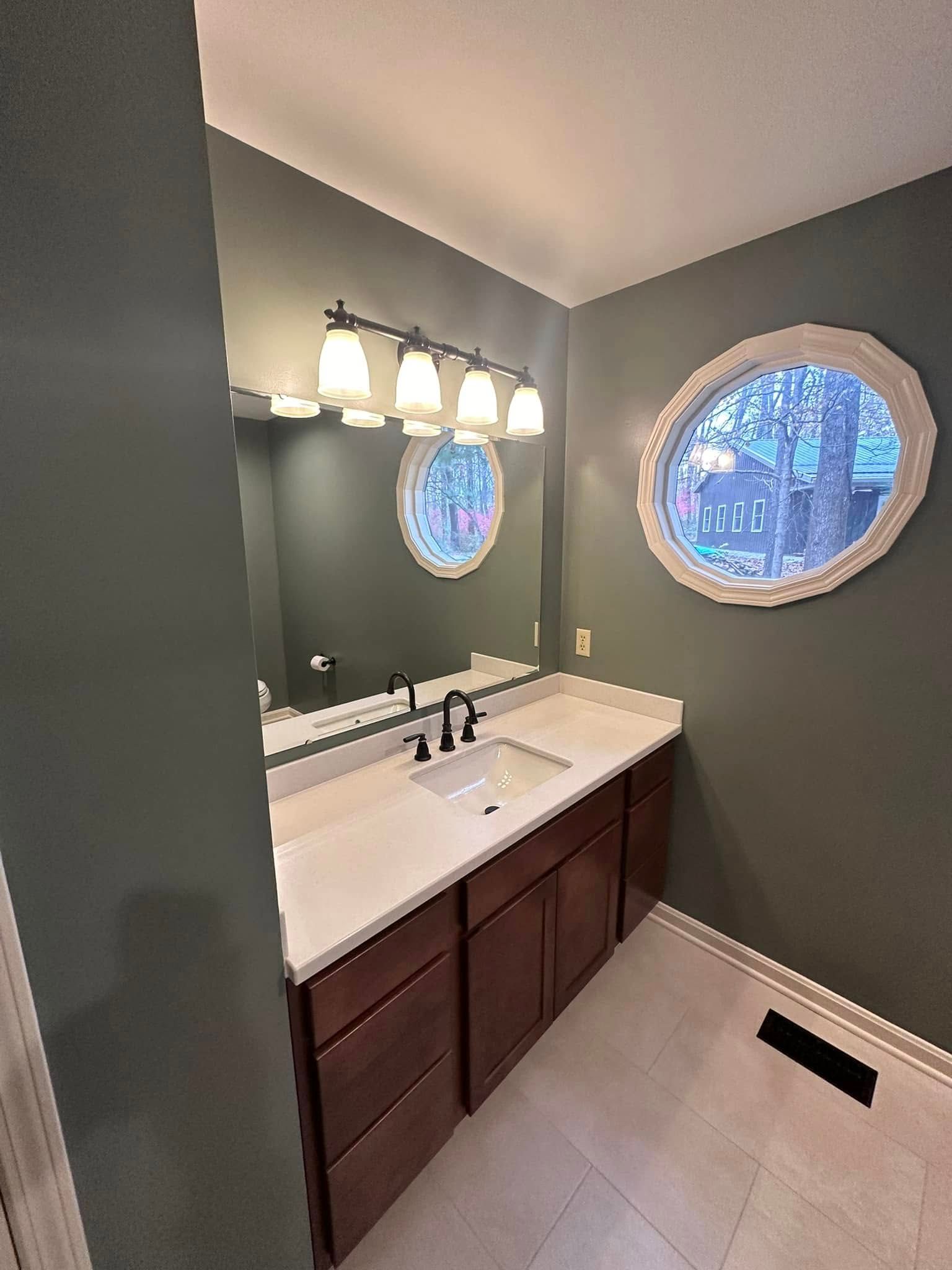 A bathroom with a sink , mirror and window.