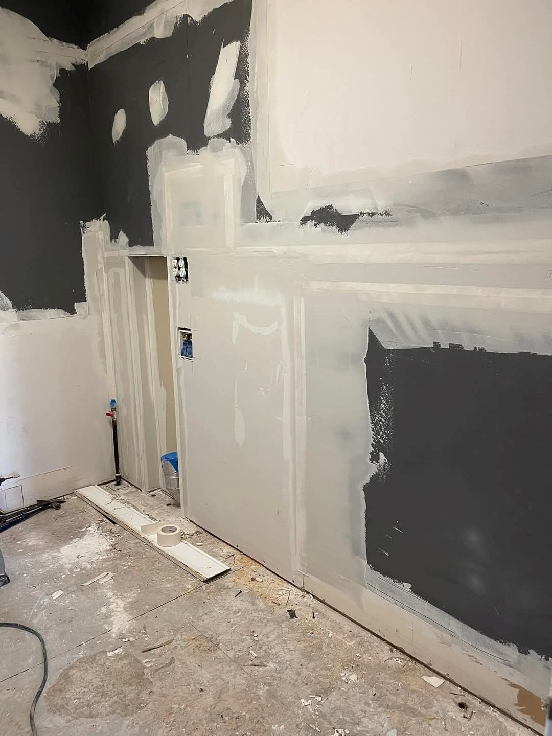 A room with a painting on the wall and a bucket of paint on the floor.