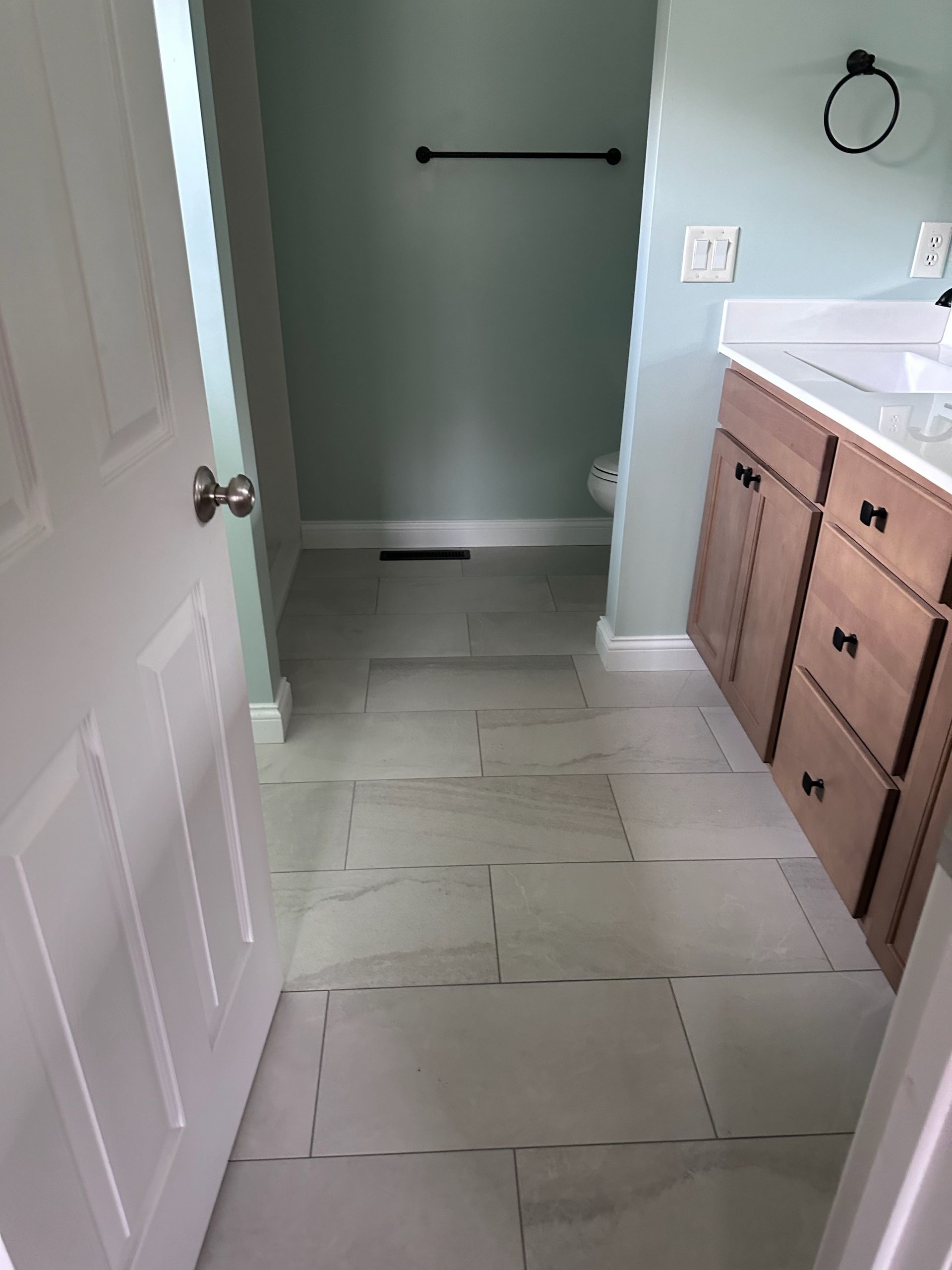 A bathroom with a tiled floor and a shower stall.