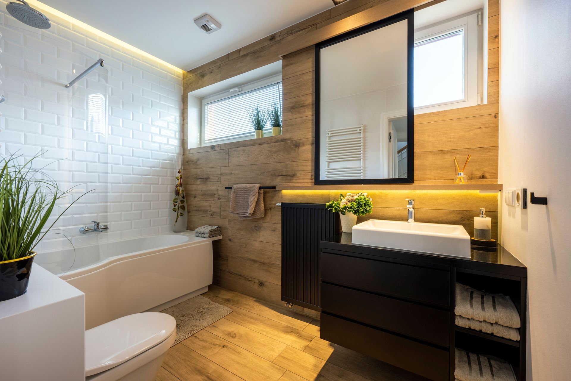 Modern bathroom with wood and white tile accents, black vanity, and large mirror.