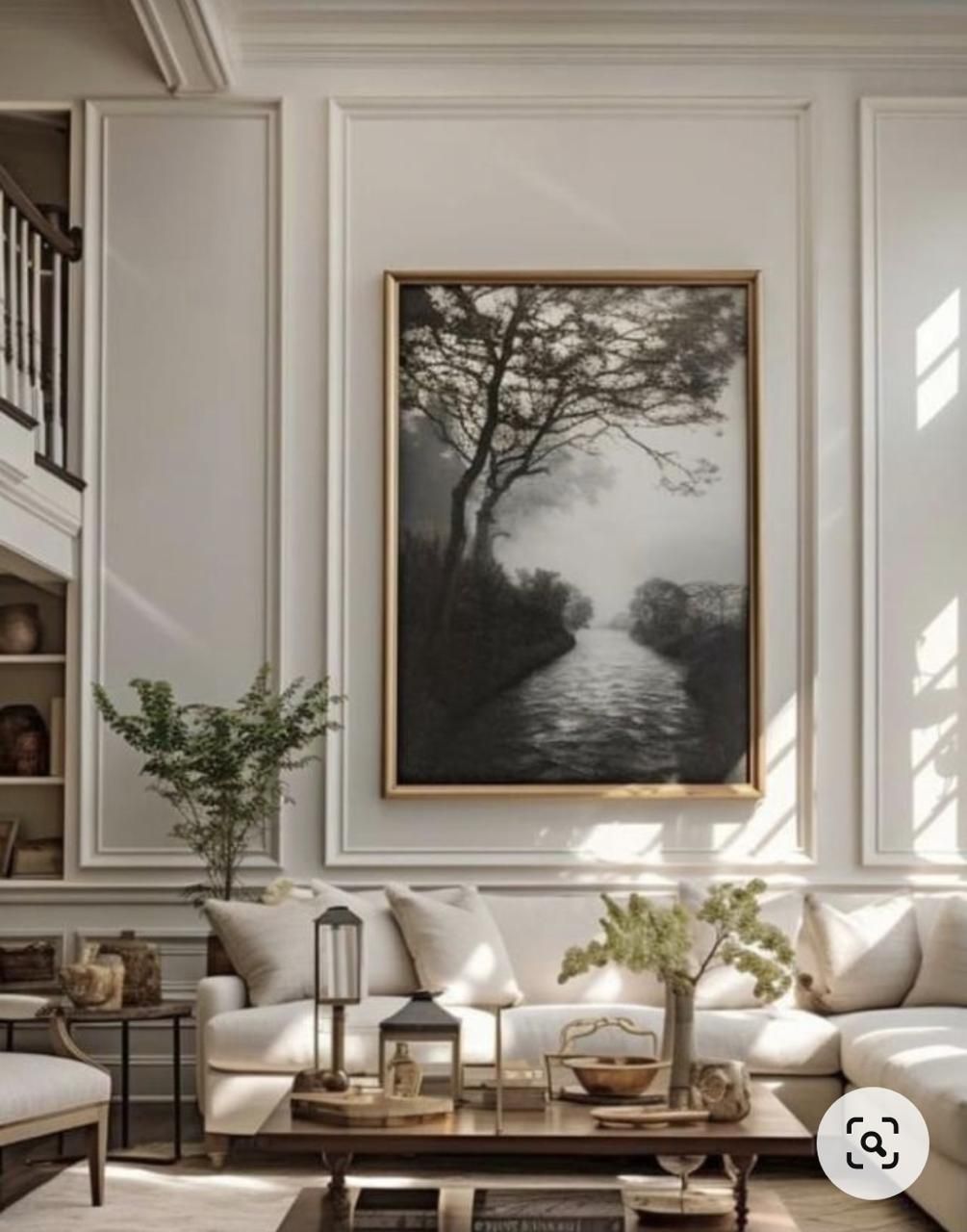 Sala de estar con tonos neutros, gran obra de arte de un río y sofá blanco.