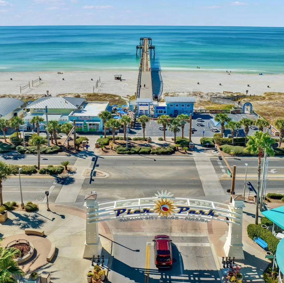 Aerial view of the Pier Park entrance sign leading to a pier stretching out over the Gulf of Mexico in Panama City Beach.