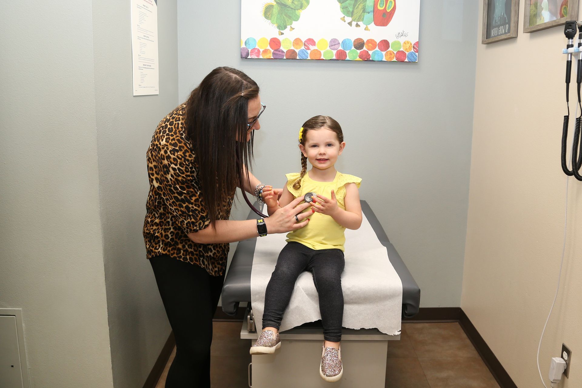 A woman is examining a little girl with a stethoscope.