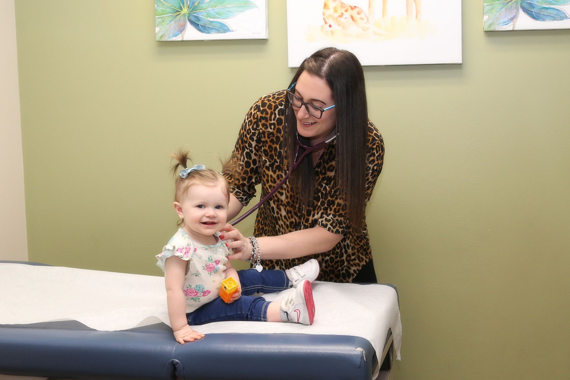 A woman is examining a little girl on a table.