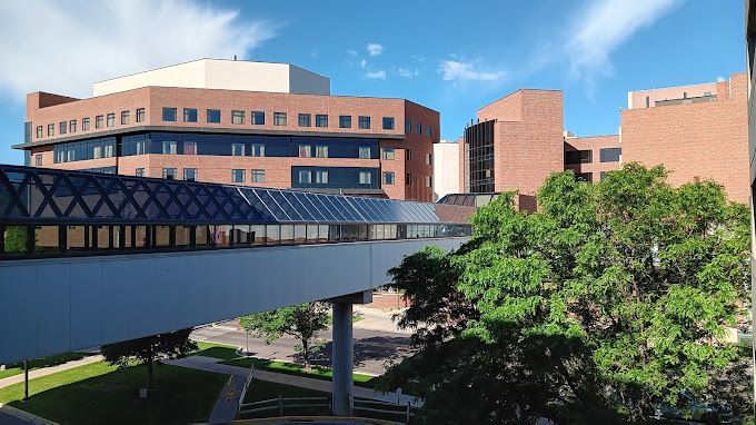 A bridge leading to a large brick building with trees in front of it.