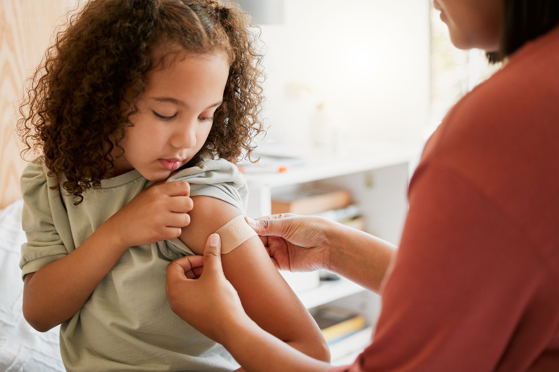 A little girl is getting a vaccine from a woman.