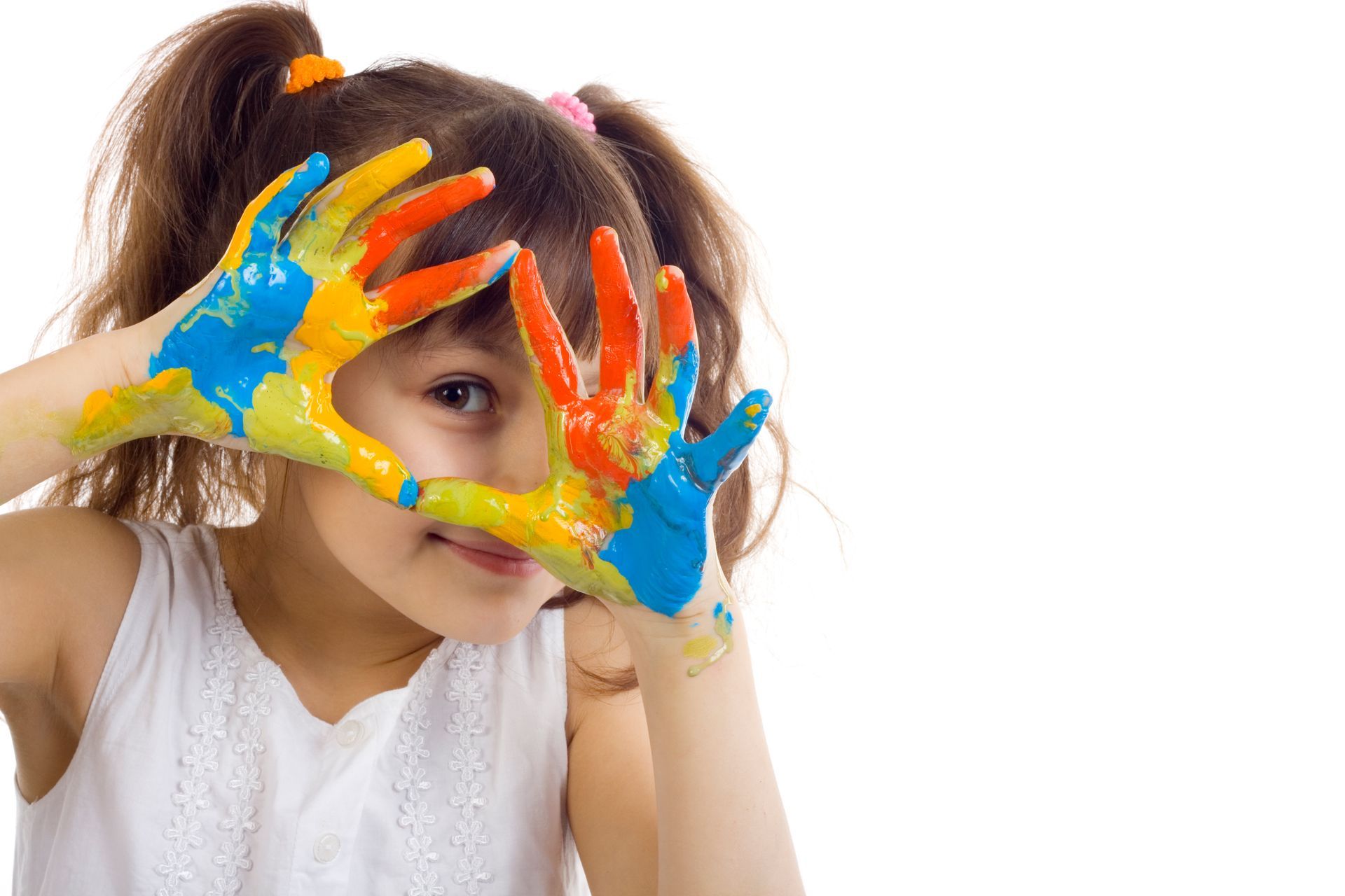 A little girl is covering her face with her hands painted in different colors.