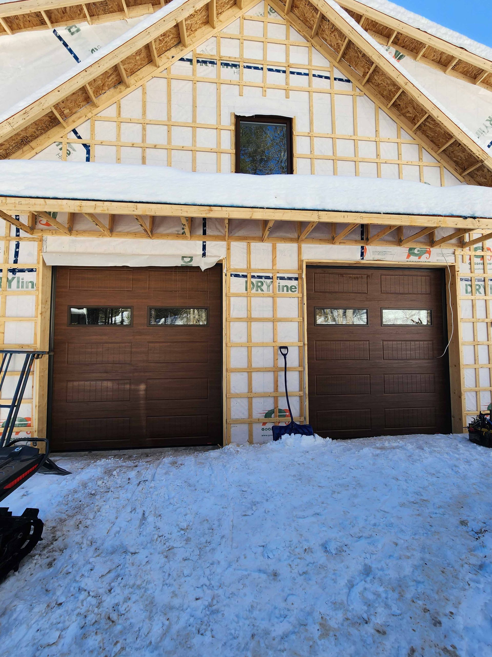 Une maison en construction avec deux portes de garage dans la neige