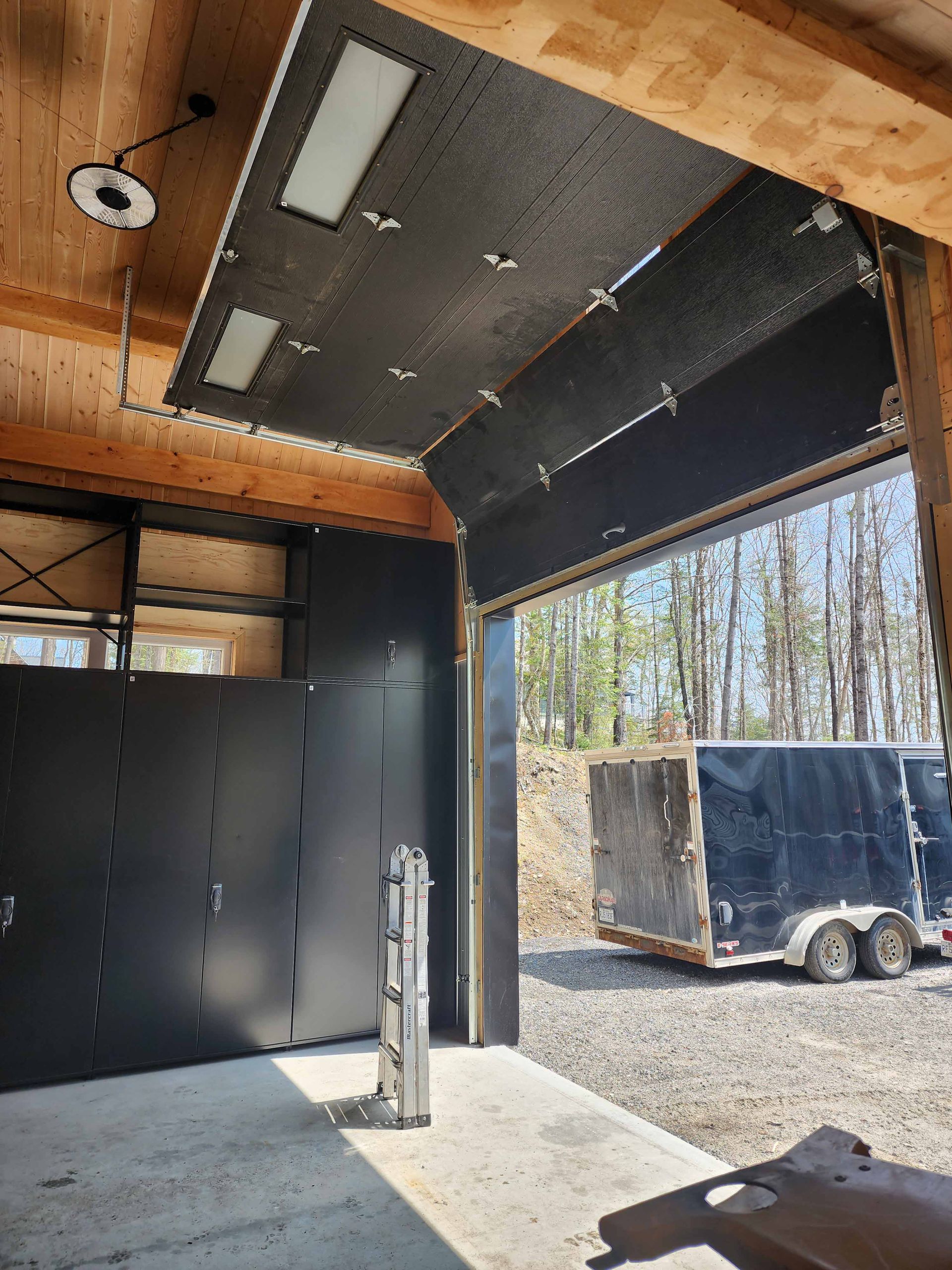 Une remorque noire est garée dans un garage avec la porte ouverte.