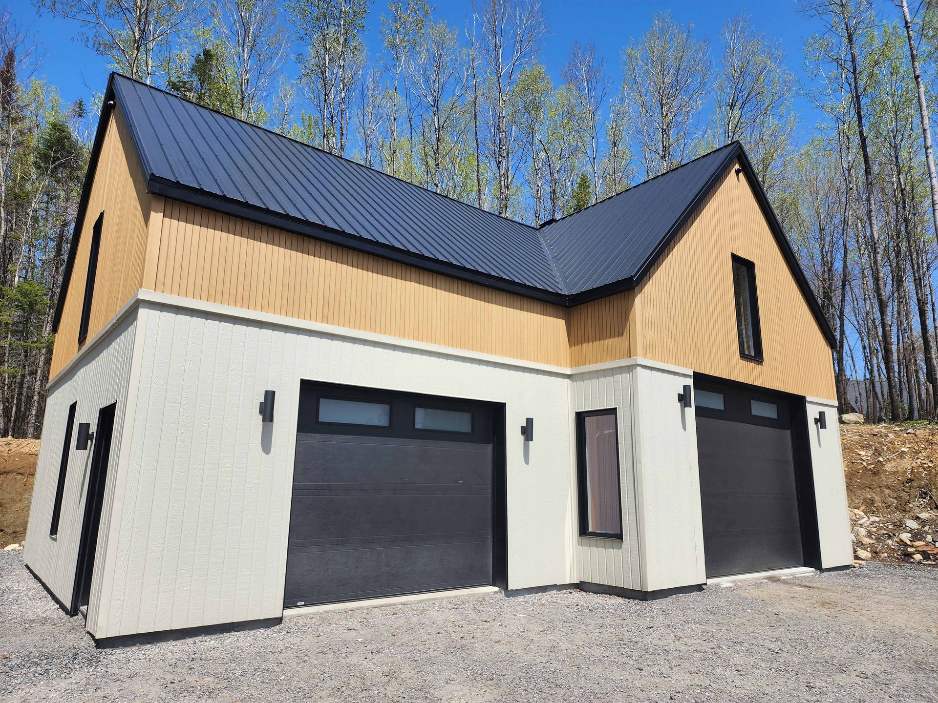 Une maison avec deux portes de garage et un toit noir